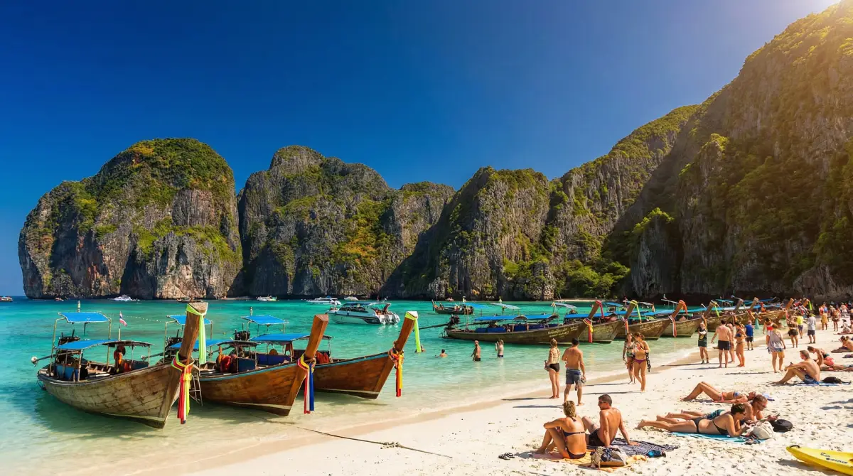 Tourists enjoying the perfect weather and clear turquoise waters of Maya Bay in Phuket during Thailand's cool season.
