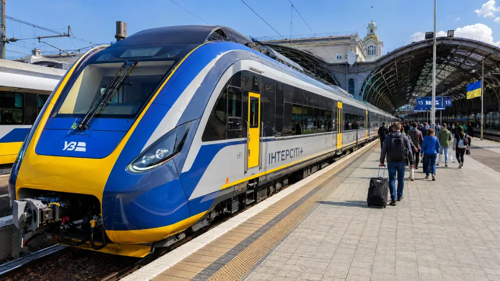 Un moderno tren interurbano ucraniano en una plataforma de estación bien iluminada durante el día.