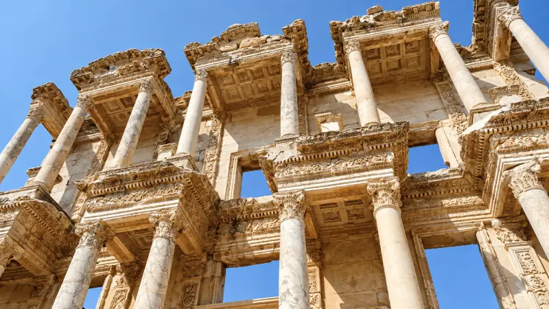 Low-angle view of the Library of Celsus façade at Ephesus, showing columns and carved upper stonework.
