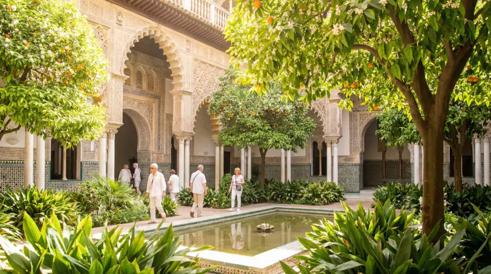 Tourists enjoying perfect spring weather in the beautiful gardens of the Real Alcazar in Seville, Spain.