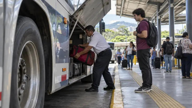 Busmedewerker laadt de weekendtas van een reiziger in het bagagevak bij een illustratieve terminal in San José.