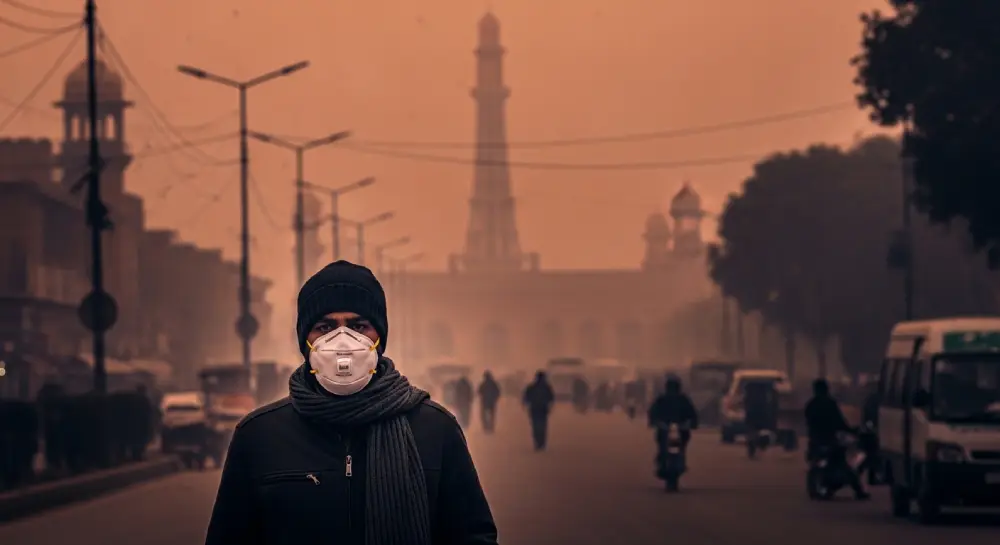 一张阴郁的照片，展示了巴基斯坦拉合尔冬季的危险空气质量（雾霾），行人佩戴N95口罩。