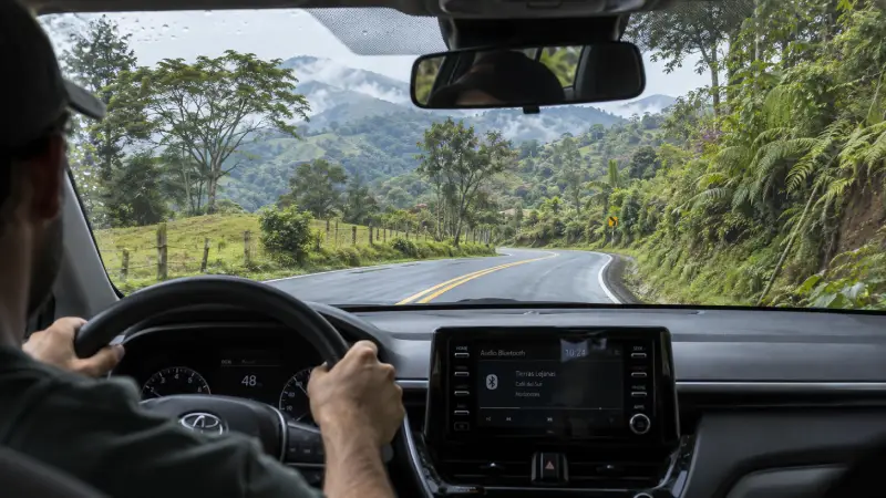 View from inside a car following a winding paved road through Costa Rica's green, lightly misty highlands.