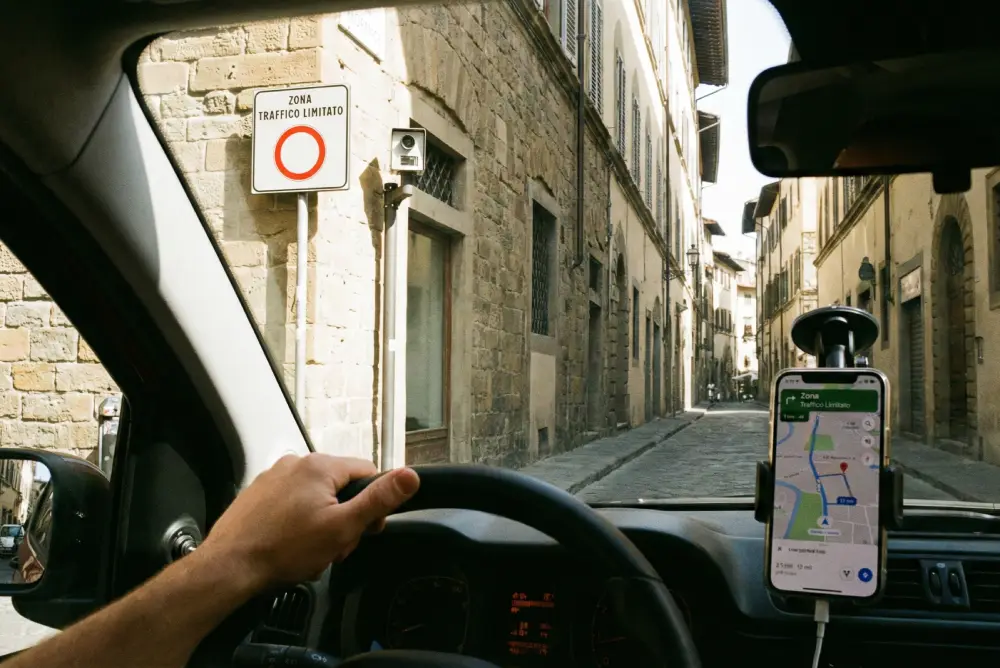 View from inside a rental car in Florence approaching a restricted ZTL zone sign and a traffic camera.