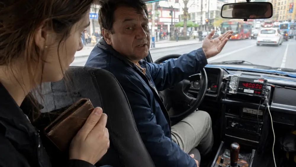 A close-up photo inside a shady Belgrade taxi, showing a confused tourist looking at a taxi meter that is visibly tampered with or covered in tape, illustrating a common tourist scam.