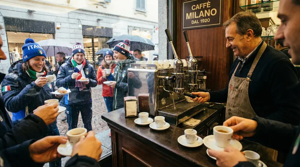 在米兰的意大利咖啡馆，粉丝和咖啡师享受浓缩咖啡，背景为2026年冬季奥运会。