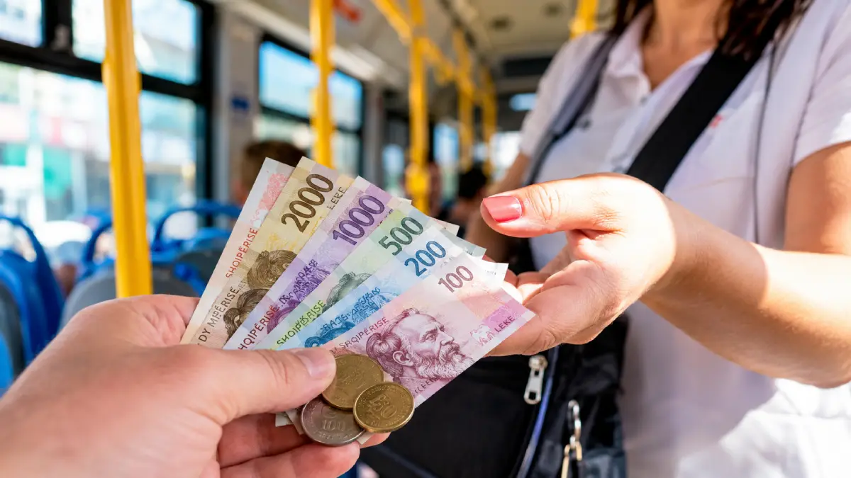 Předávání hotovosti v albánských lekech průvodčímu autobusu v Albánii.