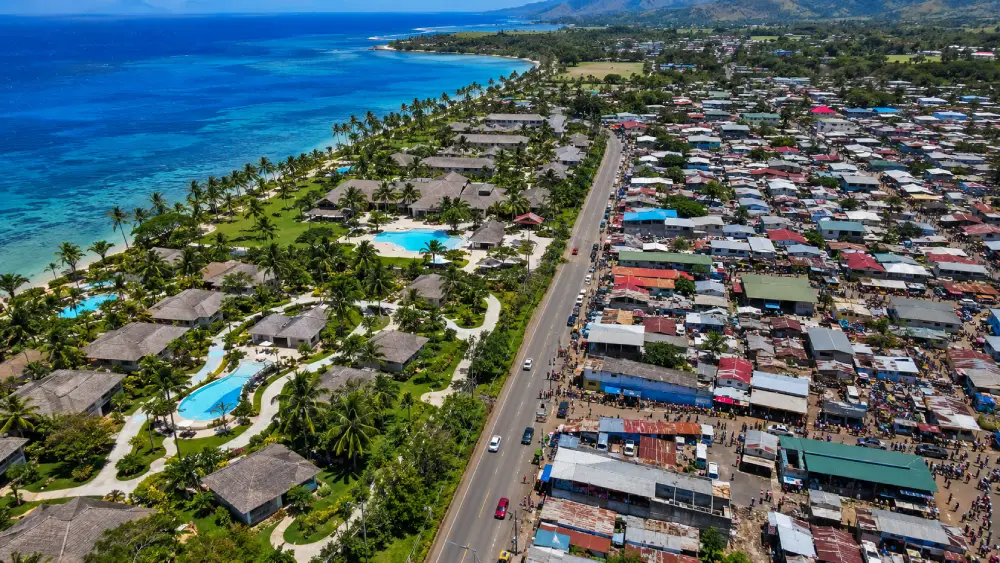 Aerial view of Viti Levu showing the stark contrast between a luxury gated resort and a bustling local town separated by a road.