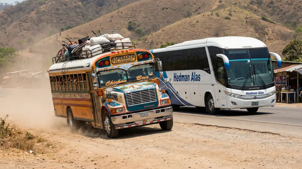 Ein überfüllter Chicken Bus, der neben einem sicheren, modernen Luxusbus auf einer Autobahn in Honduras fährt.