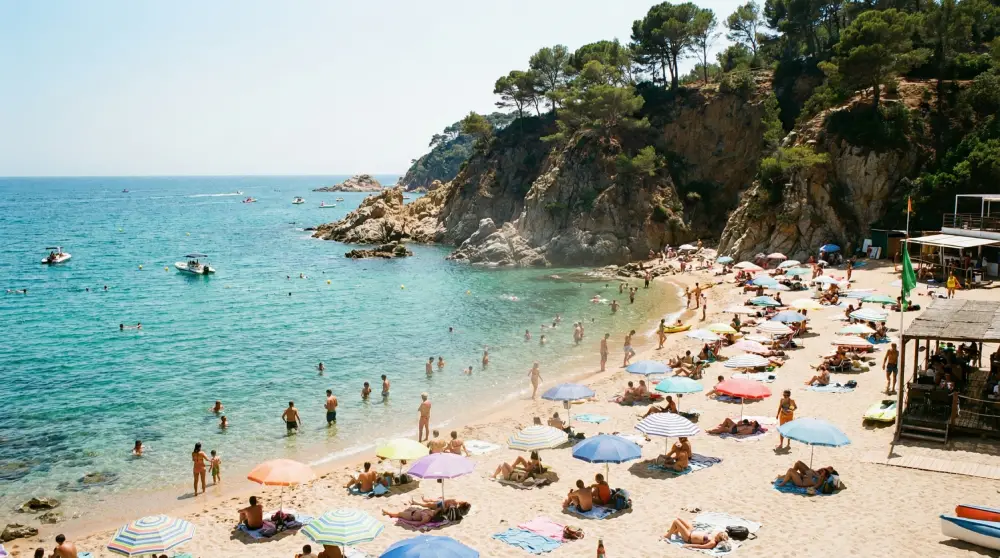 A heavily crowded Mediterranean beach in Costa Brava during the peak of Spanish summer.