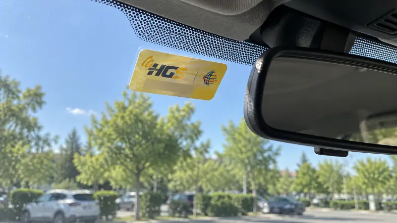 Illustrative HGS toll sticker inside a parked car’s windscreen, with account identifiers omitted.