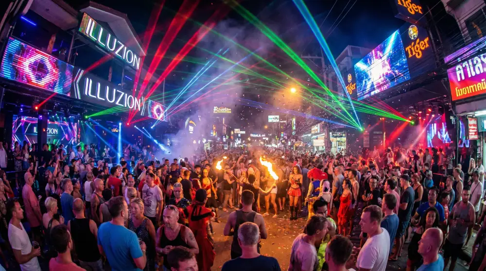 Crowded Bangla Road in Phuket at night with laser lights and tourists partying in the street.