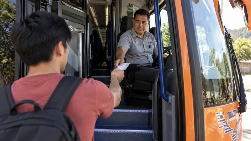 Um passageiro mostra uma passagem de papel ao motorista ao embarcar em um ônibus intermunicipal da Costa Rica.
