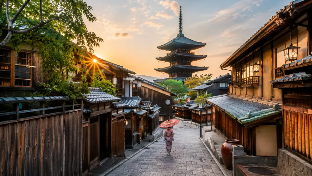 A peaceful morning scene in Kyoto's Higashiyama district, showing traditional wooden houses and the Yasaka Pagoda under a warm sunrise.